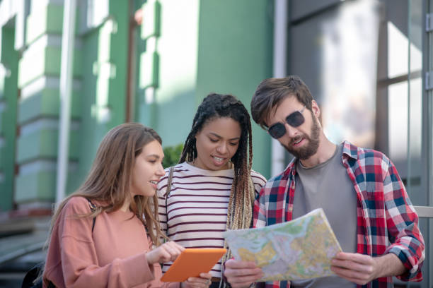 istock Guy with map and two girls with tablet 1255218930