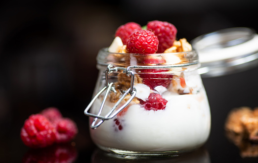 Delicious fruit parfait with pudding and cream topped with raspberry fruit in a jar