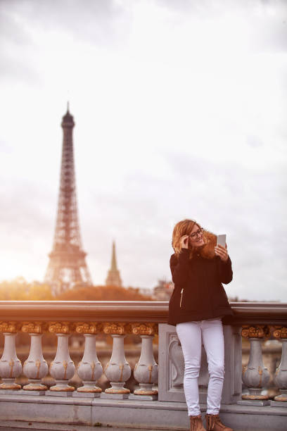 istock Girl using cellphone with Paris city background, Seine river and Eiffel tower. 1255225897