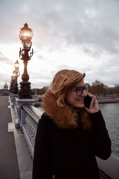 istock Girl using cellphone with Paris city background, Seine river. 1255225935
