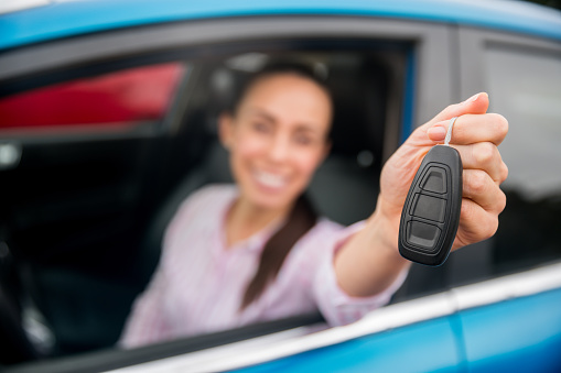 Driver holding the keys of her new car and going for a test drive â focus on foreground