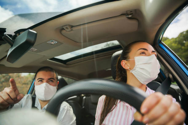 Passenger pointing the way to the driver while riding on a car Passenger pointing the way to the driver while riding on a car wearing facemasks - pandemic lifestyle concepts car pooling photos stock pictures, royalty-free photos & images