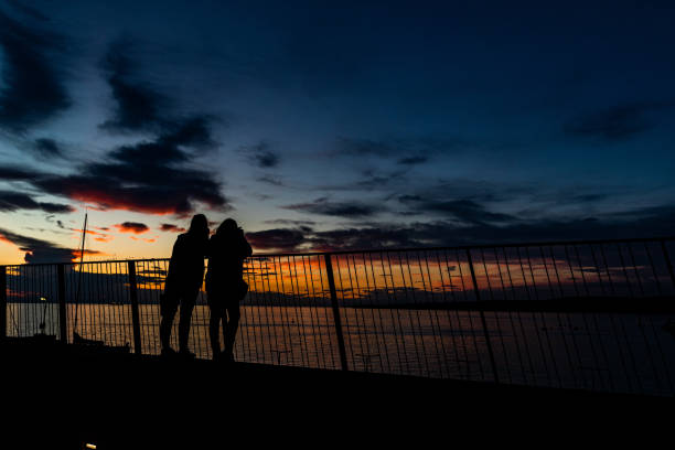 Particular view of two persons looking at the sundown above the sea, harbor of Koper, Slovenia.