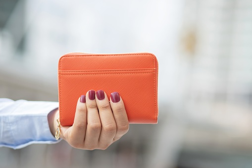 Woman holding a fashion wallet, she is shopping at a department store.
