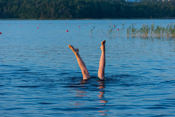 istock A person standing upside down in a lake. Legs visible over water 1255229898