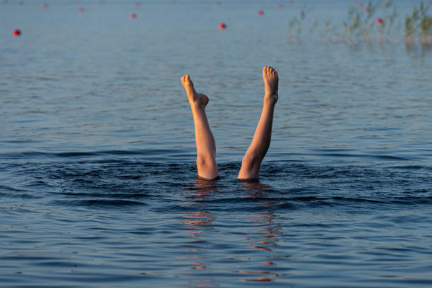 istock A person standing upside down in a lake. Legs visible over water 1255229904
