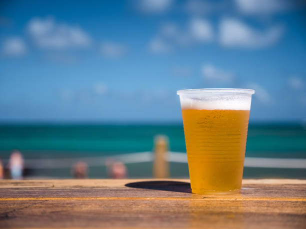 istock Beer in plastic cup on wooden table over caribbean sea background 1255230016