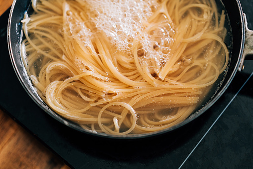 Close-up of spaghetti pasta In boiling hot water in steel pan. Preparation for making Al Dente Spaghetti.
