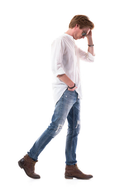 istock Side view of walking young sad man looking down concerned with bowed head. 1255243052