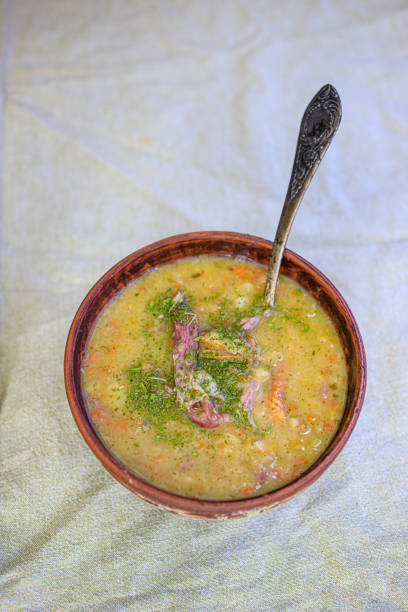 istock Pea soup with smoked meat, crackers and herbs in a rustic clay plate on a light linen tablecloth. Minimalism Life style, naturalness. Copy space 1255245476