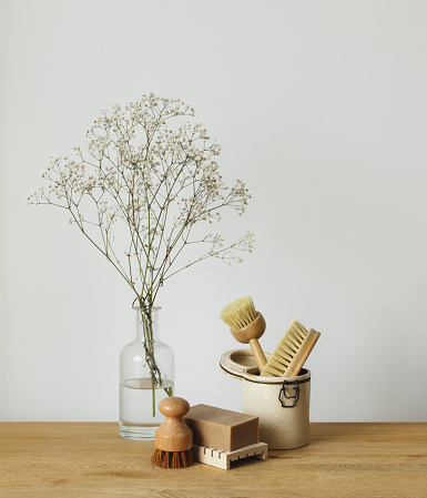 Natural wooden dish brushes and vase with flowers