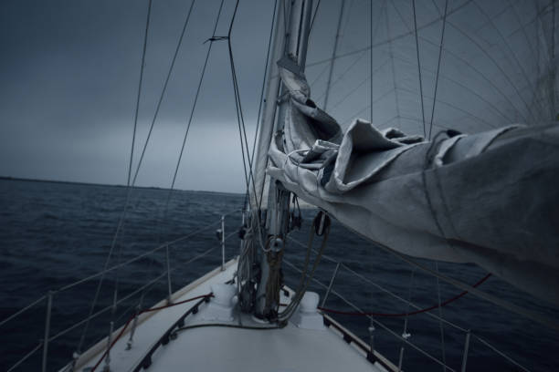 yachtsegeln im gewitter an einem regnerischen herbsttag. von oben nach unten blick vom deck zum bug, mast und segel. dramatischer stürmischer himmel, dunkle wolken. norwegen - sailing cable winch yacht sport stock-fotos und bilder