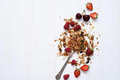 Granola with nuts, coconut and berries on a white wooden background. View from above.