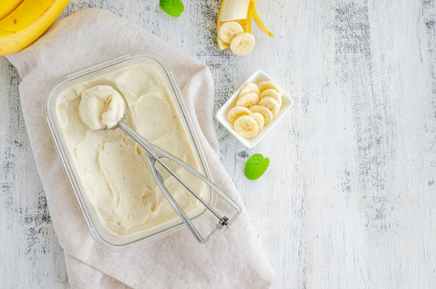 Homemade banana ice cream in a glass container with a spoon for ice cream on a wooden background. Healthy dessert. Horizontal, top view, copy space. Homemade banana ice cream in a glass container with a spoon for ice cream on a wooden background. Healthy dessert. Horizontal, top view, copy space homemade icecream stock pictures, royalty-free photos & images