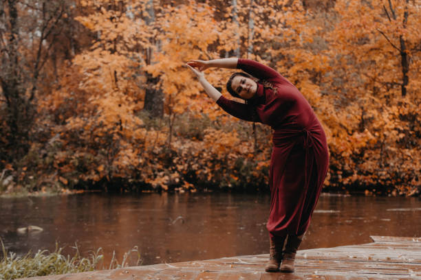 Plus size girl doing yoga in autumn park.