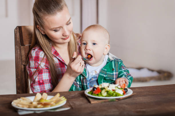 istock Mother feeding child. First solid food for young kid. 1255256160