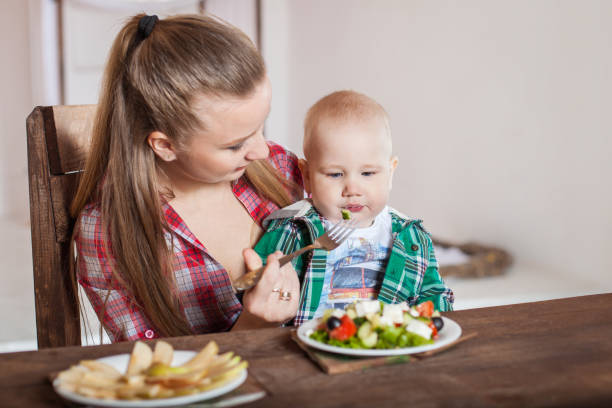 istock Mother feeding child. First solid food for young kid. 1255256167