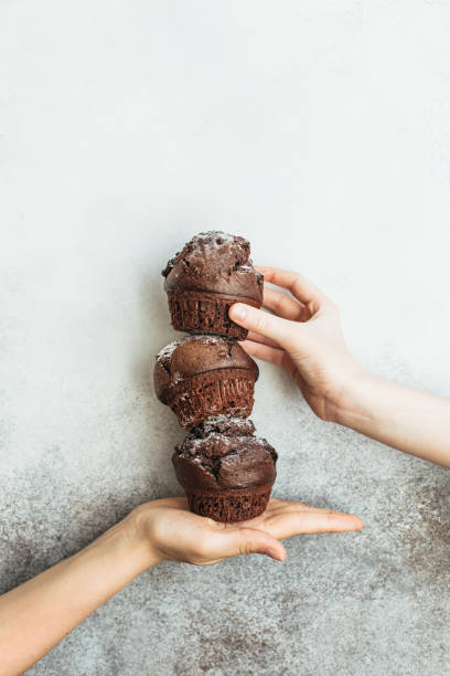 istock Three chocolate cupcakes stand in the palm of your hand 1255260464