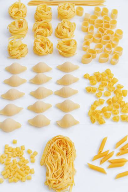 istock Various uncooked pasta on white wooden background. Top view. Italian pasta for restaurant with space for text. 1255261241