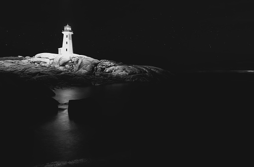 Peggy's Cove Lighthouse is illuminated with light from above. Long exposure with drone light painting.