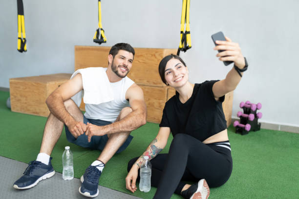istock Woman Taking Selfie With Man In Gym 1255263780