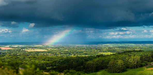 A dramatic storm scene over a rural field with a rainbow