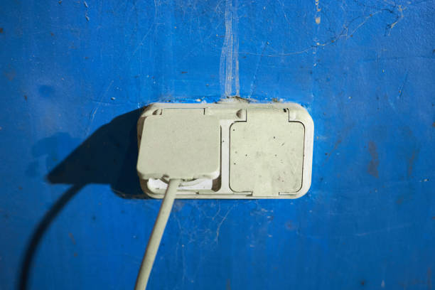 power socket at blue concrete wall. minimal concept. electric socket with hard shadow. indoors.
