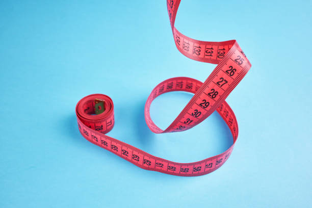 istock weight loss measuring concept. red centimeter balancing  over blue background. 1255272315