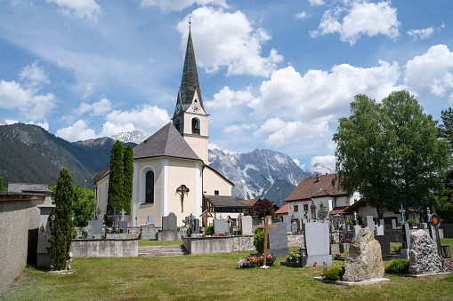 Traditional Austrian village church and cemetery in the sunny alpine mountains, Obsteig, Tirol, Austria