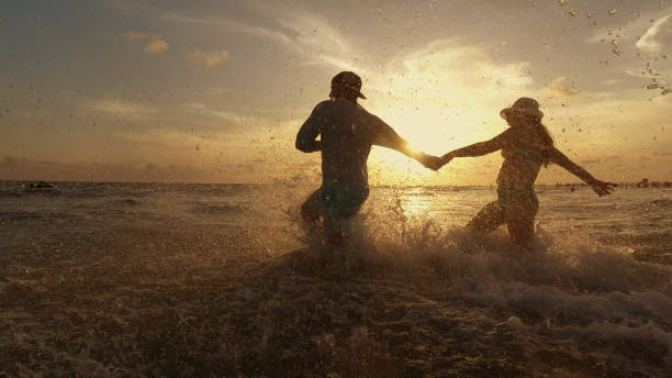 Young hispanic couple running into the water