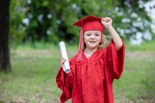 Preschool graduate raises arm in celebration for completing the school year