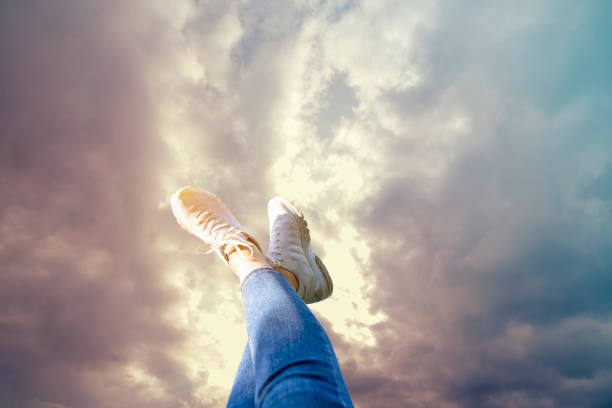 istock Female feet with white shoes and sky. copy space for advertisements, logos or texts 1255285341