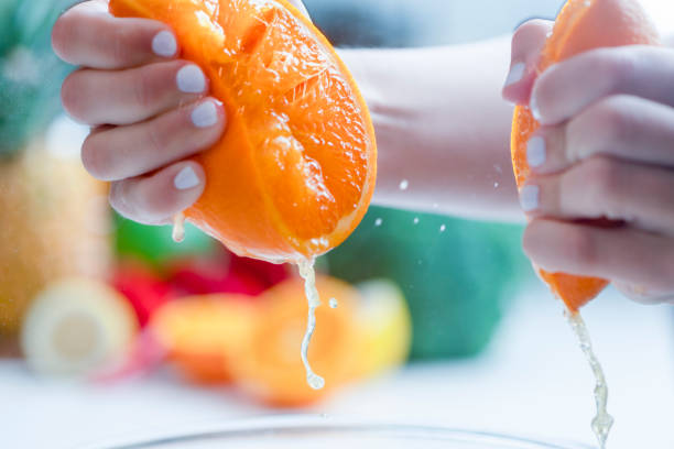 istock Woman squeezing the juice from an orange. 1255285447