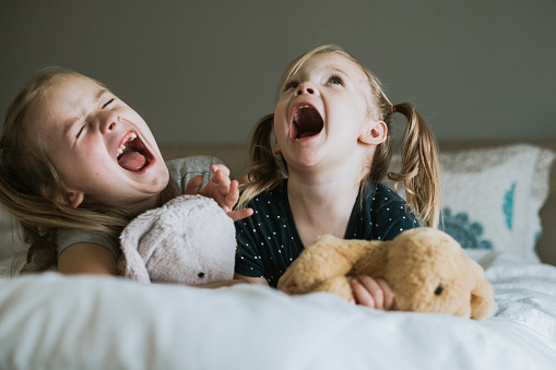 Funny preschool and elementary age sisters yell and sing loudly while playing