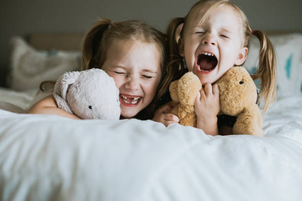 istock Sisters laugh while playing with stuffed animals at home in bedroom 1255285513