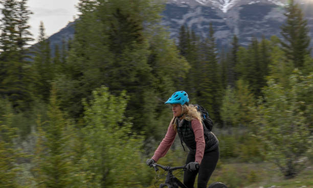 istock Female mountain e-biker rides along forested trail 1255286303