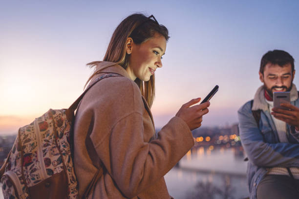 istock Young woman text messaging on a mobile phone next to her boyfriend 1255286433
