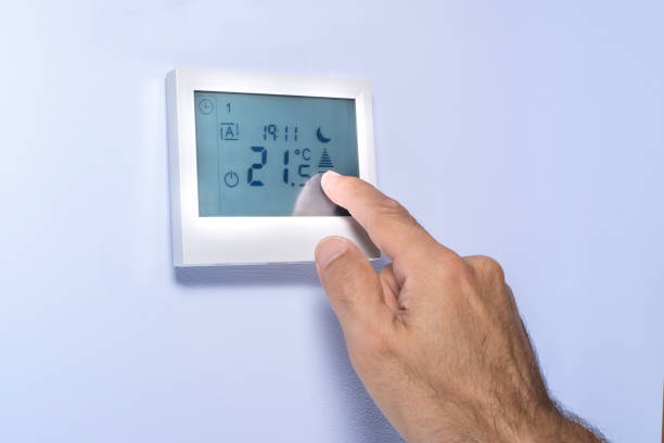 istock hand pressing on a touch screen of a thermostat 1255287254