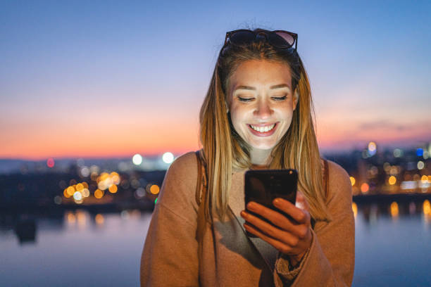 istock Cute young woman smiling while text messaging on a mobile phone 1255287279