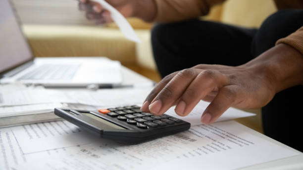 istock Close up black man hand using calculator and laptop. 1255292031