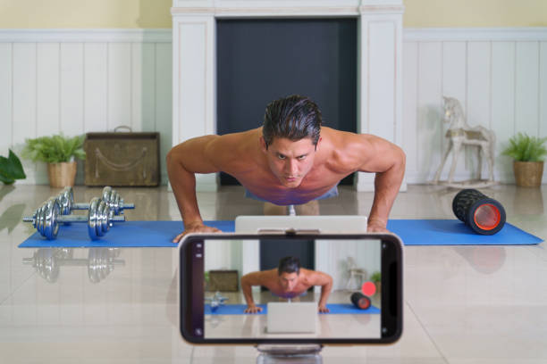 istock caucasian athletics vlogger and blogger as workout coach broadcasting live online using smartphone show workout technics at home during coronavirus covid-19 lock down 1255297239