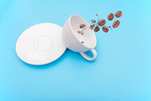 istock Overturned or knocked over white coffee cup, mug with bowl and coffee beans on blue background, concept picture 1255299868
