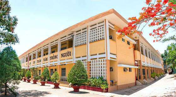 Tien Giang, Vietnam - May 10th, 2020: High school in summer full of phoenix flowers, this is also the cradle of knowledge to help children grow up to help society in Tien Giang, Vietnam
