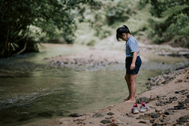 an asian chinese young girl playing in the river having fun during weekend recreational pursuit - children only tree area exploration freshness imagens e fotografias de stock