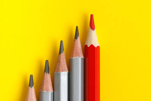 istock red pencil and gray pencils on a yellow paper background.Text 1255326047
