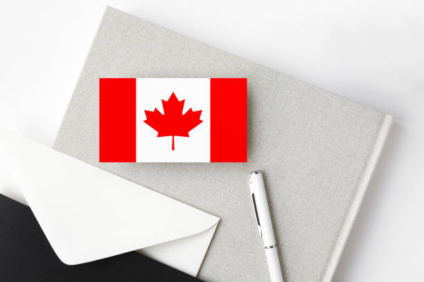 istock Canada flag on minimalist letter background. National invitation envelope with white pen and notebook. Communication concept. 1255329482