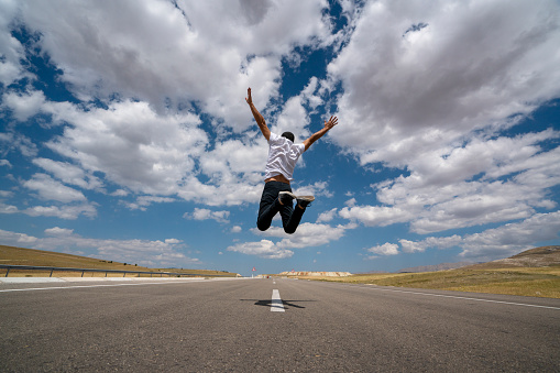 Young man jumping high up over the road