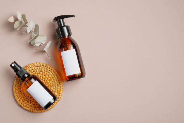 istock Amber glass cosmetic bottles mockups with blank labels and eucalyptus leaf on beige background. Natural organic beauty product packaging design. Flat lay, top view. 1255337019