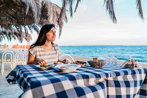 Young beautiful caucasian woman having a dinner by the sea.