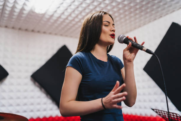 istock Young woman singing in recording studio 1255338717
